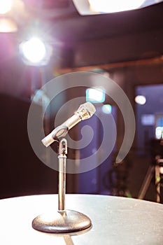 Microphone in the recording studio, equipment and lighting in the blurry background