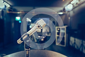 Microphone in the recording studio, equipment and lighting in the blurry background