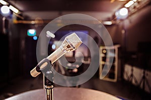 Microphone in the recording studio, equipment and lighting in the blurry background