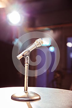 Microphone in the recording studio, equipment and lighting in the blurry background