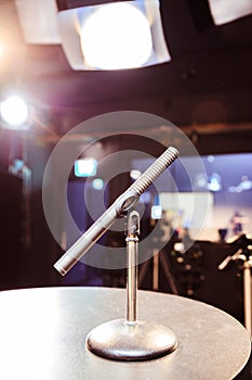 Microphone in the recording studio, equipment and lighting in the blurry background