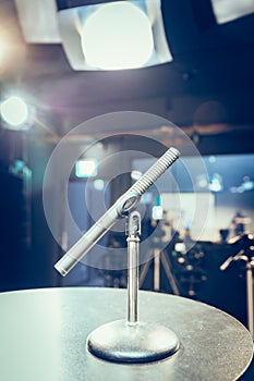 Microphone in the recording studio, equipment and lighting in the blurry background