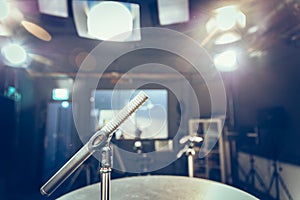 Microphone in the recording studio, equipment and lighting in the blurry background