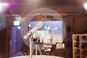 Microphone in the recording studio, equipment and lighting in the blurry background