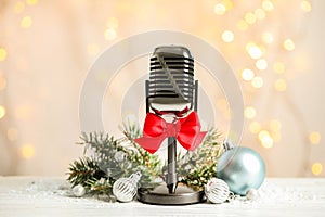 Microphone with red bow and decorations on  table against blurred lights. Christmas music