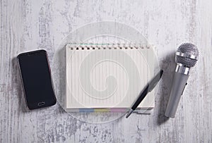 Microphone, smartphone, notepad and pen on the modern desk