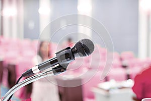 Microphone on stage with conference hall blurred pink background