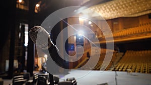 Microphone on the stage and empty hall during the rehearsal. Microphone on stage with stage-lights in the background