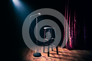 Microphone and wooden stool on a stand up comedy stage with reflectors ray, high contrast image