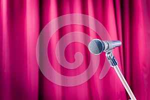 Microphone on a stand with blurred red curtain, copyspace on the