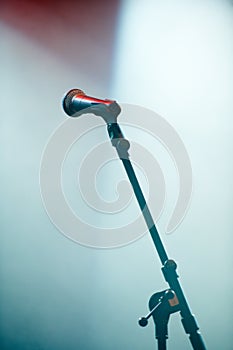 Microphone stand, empty room and stage for karaoke in spotlight for audio performance with singing. Concert, technology