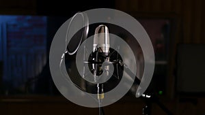 Microphone on a stand located in a music studio recording booth under low key light