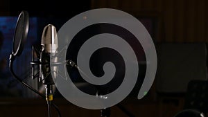 Microphone on a stand located in a music studio recording booth under low key light