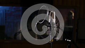 Microphone on a stand located in a music studio recording booth under low key light