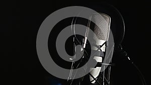 Microphone on a stand located in a music studio recording booth under low key light