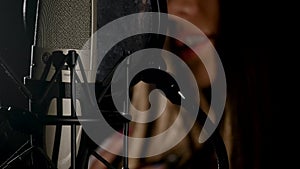 Microphone on a stand located in a music studio recording booth under low key light