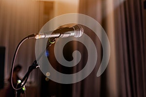Microphone on stand on stage close up with searchlight light. Professional mic at concert hall or conference room