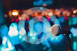 microphone on a stand up comedy stage with colorful bokeh , high contrast image.