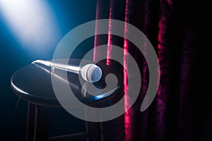 Microphone on a wooden stool on a stand up comedy stage with reflectors ray, high contrast image