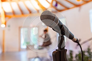 Microphone on a straight stand, with blurry woman giving a conference photo