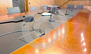 Microphone on a wooden table and empty chairs in a boardroom