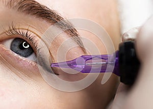 Micropigmentation Concept. Beautician doing permanent make up eyeliner procedure to young woman