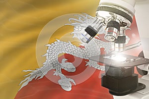 Microscope on Bhutan flag background - science development concept. Research in clinical medicine or microbiology 3D illustration