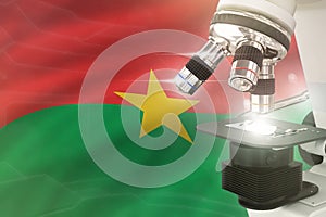 Microscope on Burkina Faso flag background - science development concept. Research in pharmaceutical industry or microbiology 3D