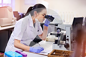 Microscope, female scientist and analyse in laboratory for research or medical breakthrough. Notes, data and health with photo