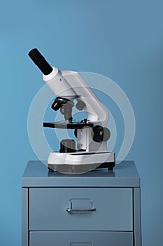 Microscope on laboratory cabinet against blue background