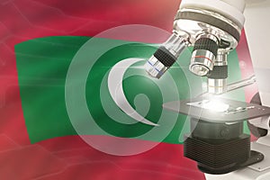 Microscope on Maldives flag background - science development concept. Research in medicine or vaccine 3D illustration of object