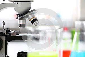 Microscope standing in school chemistry lab among bottles