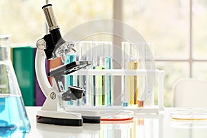 Microscope on table with laboratory equipment in chemical lab with light flare