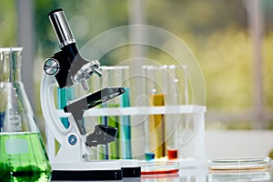 Microscope on table with laboratory equipment in chemical lab