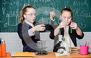 Microscope and test tubes on table. Perform chemical reactions. Basic knowledge of chemistry. Girls classmates study