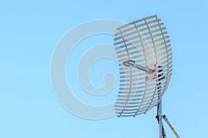 Microwave antenna dish on blue sky background.