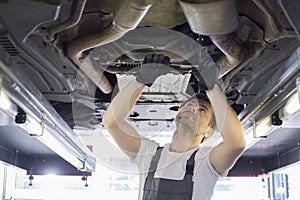 Mid adult automobile mechanic repairing car in workshop