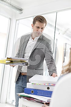 Mid adult businessman burdening employee with work in office