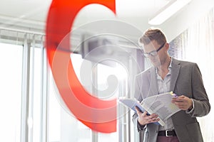 Mid-adult businessman reading file in creative office