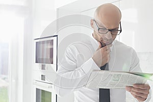 Mid adult businessman reading newspaper at home