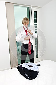 Mid adult businessman tying tie in bedroom