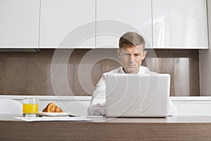 Mid adult businessman using laptop at breakfast table