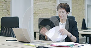 Mid-adult caucasian businesswoman comparing data online and tearing diagrams. Portrait of stressed elegant woman working