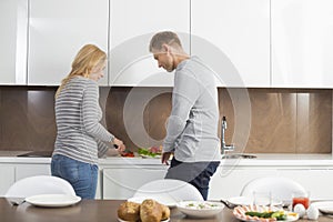 Mid adult couple preparing meal together in kitchen