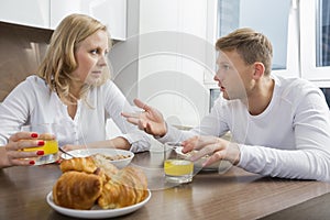 Mid adult couple talking while having breakfast at home