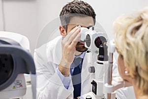 Mid adult doctor examining patient on phoropter at hospital