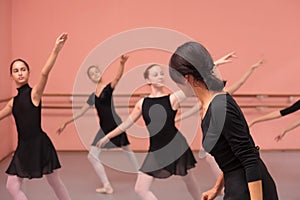 Mid adult female ballet teacher instructing medium group of teenage girls