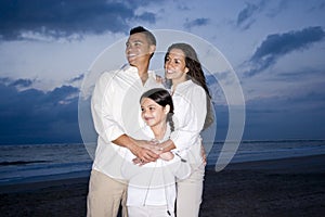 Mid-adult Hispanic family smiling on beach at dawn