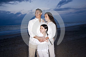 Mid-adult Hispanic family smiling on beach at dawn