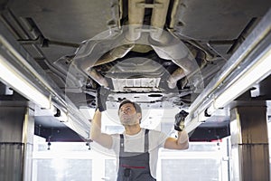 Mid adult male repair worker repairing car in workshop